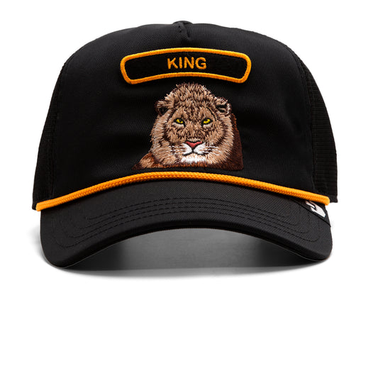 Schwarze Trucker-Cap mit gesticktem Löwenkopf und orangem "King"-Patch oben, orangene Kante am Schirm.